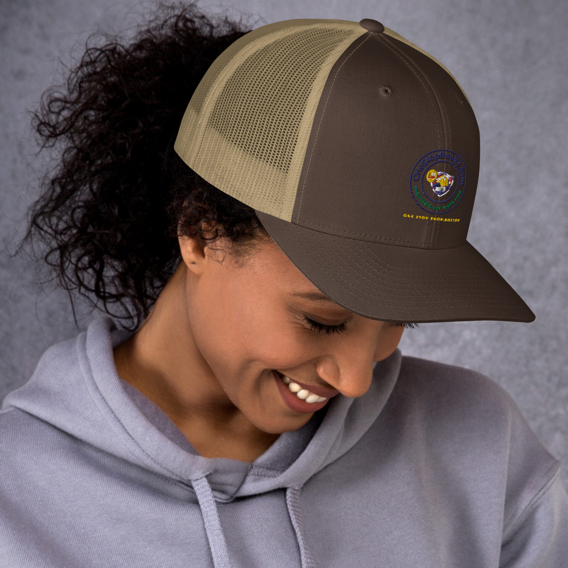 Woman smiling, wearing a brown and tan hat.