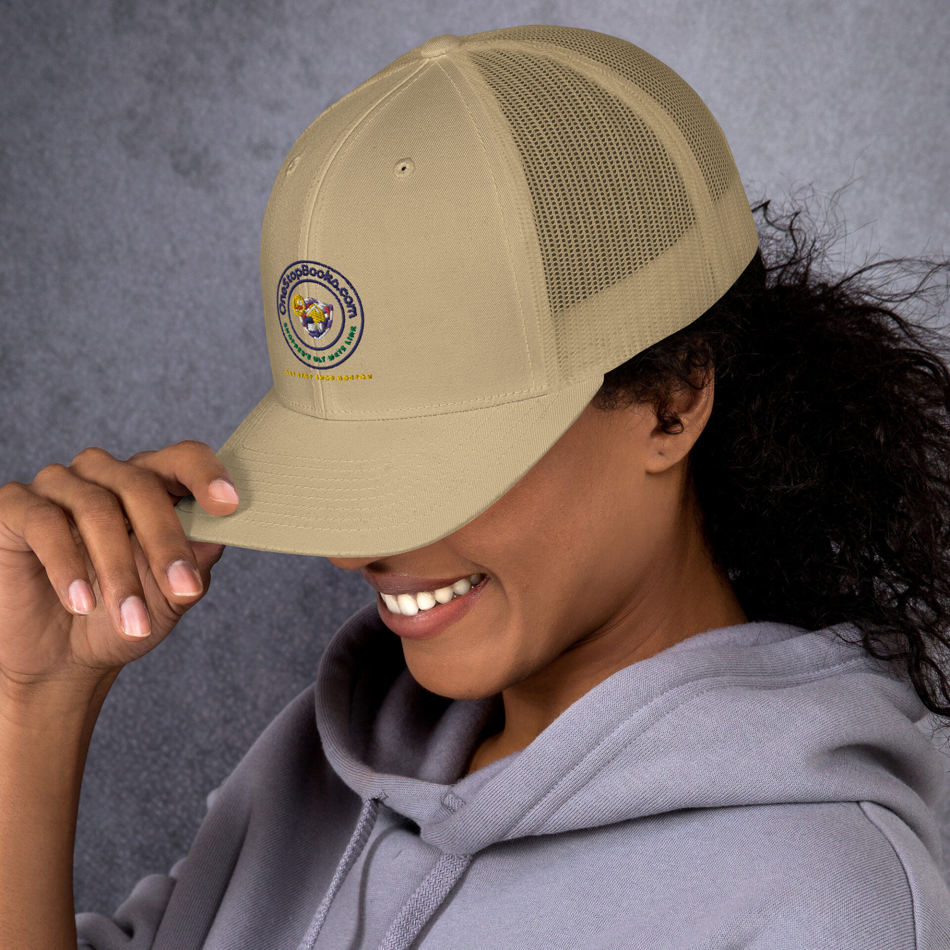 Person wearing a beige trucker hat with logo.
