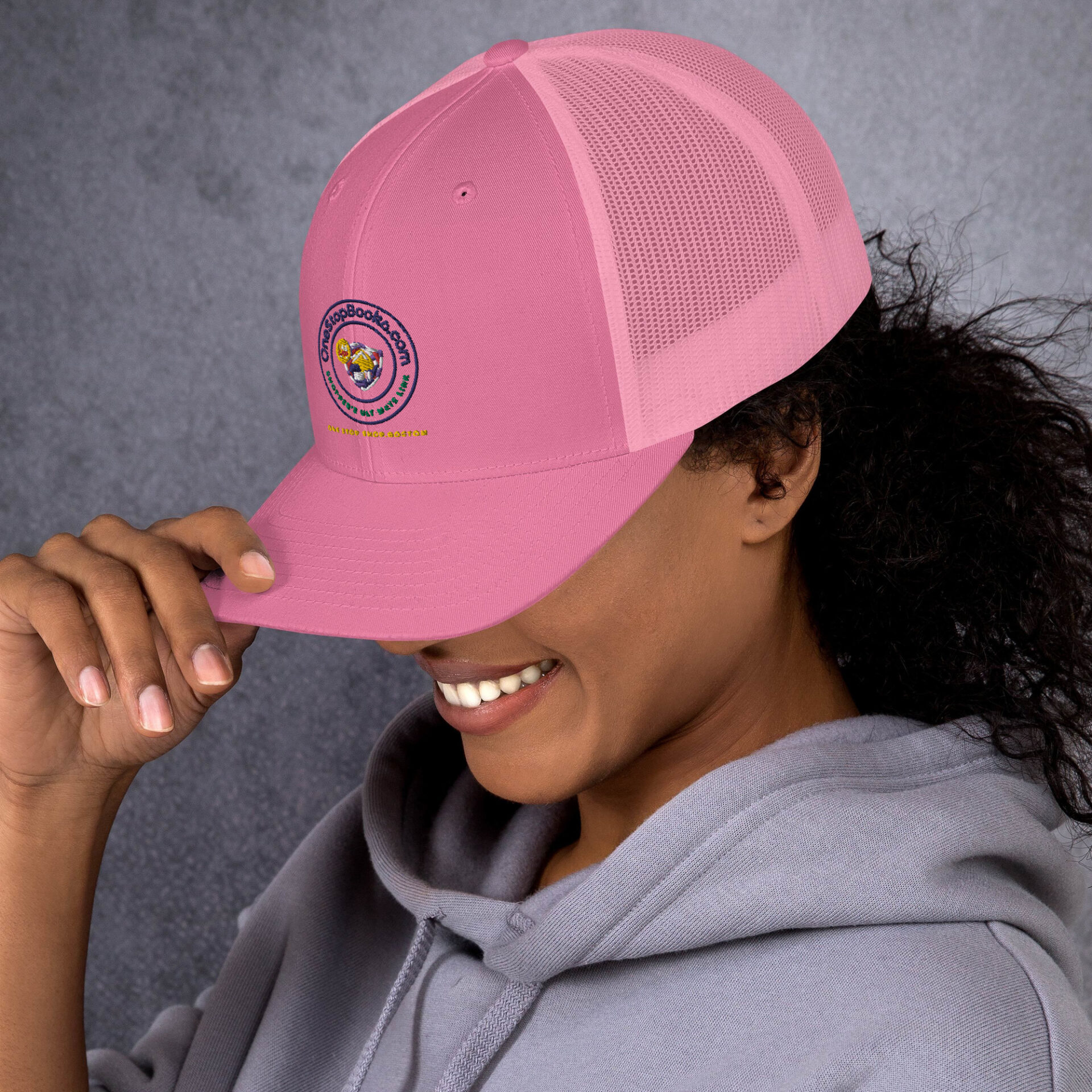 Woman wearing pink trucker hat with logo.