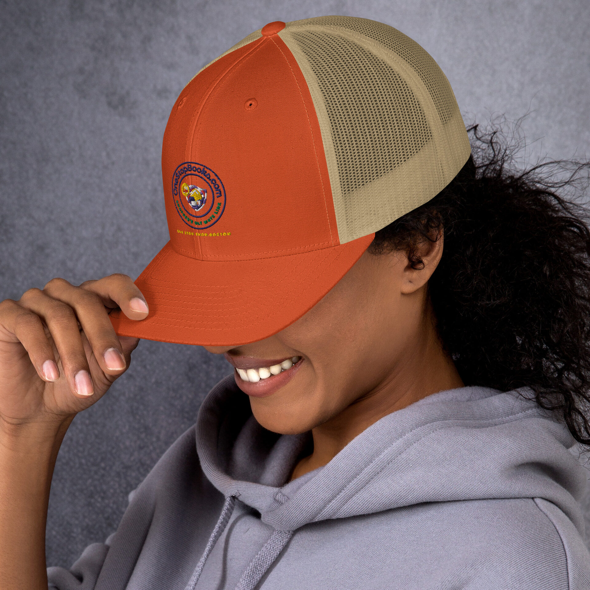 Woman smiling while wearing a red and beige hat.