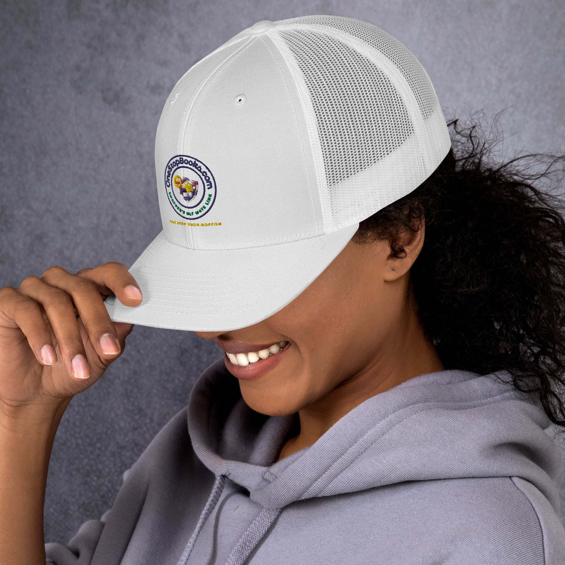 Woman smiling in white trucker hat.