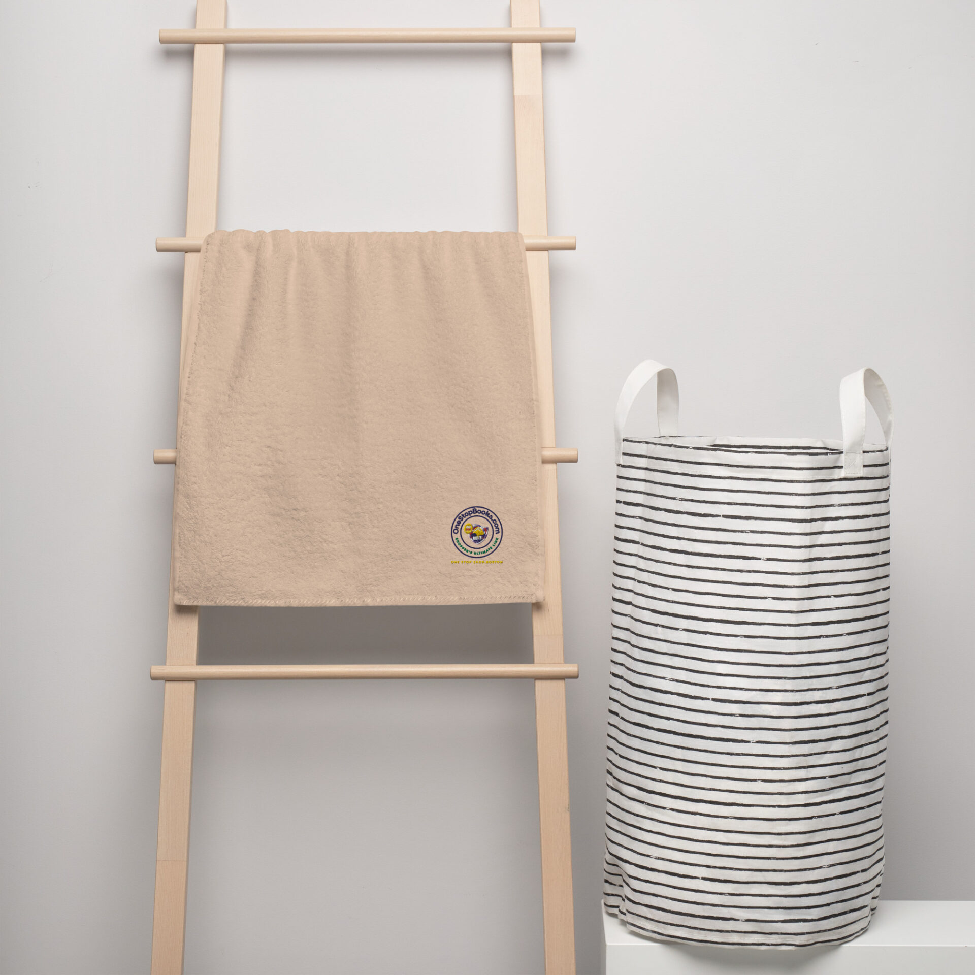 Beige towel on wooden rack with striped laundry basket.