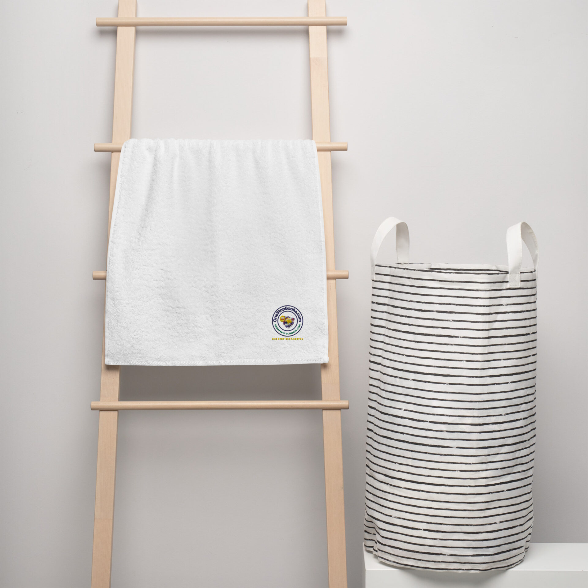 White towel on a wooden rack with a striped laundry basket.