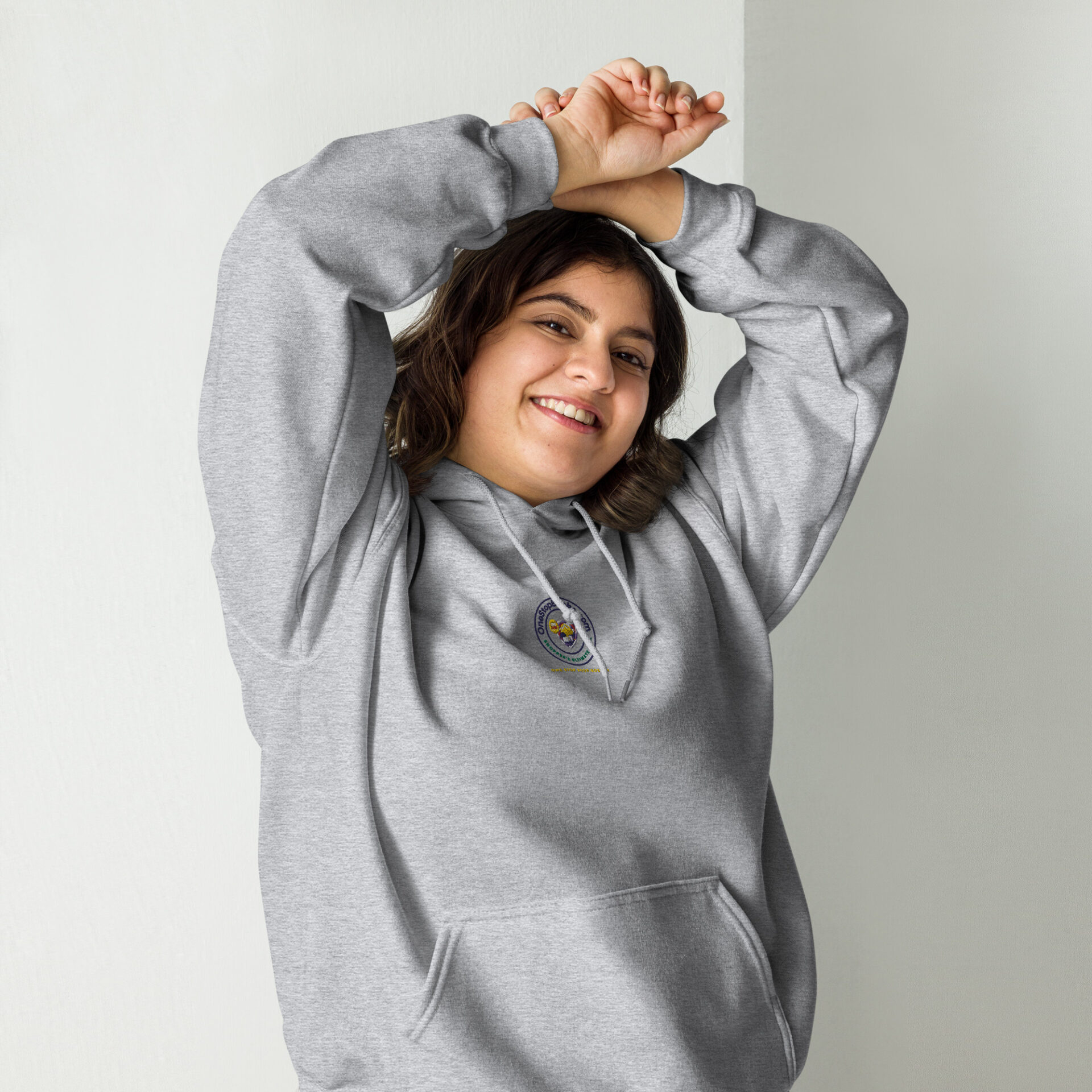 Smiling woman in gray hoodie with logo.