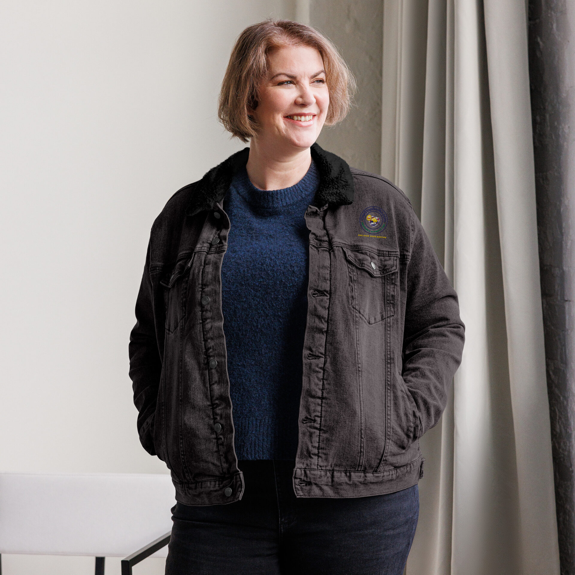 Smiling woman in a black denim jacket.