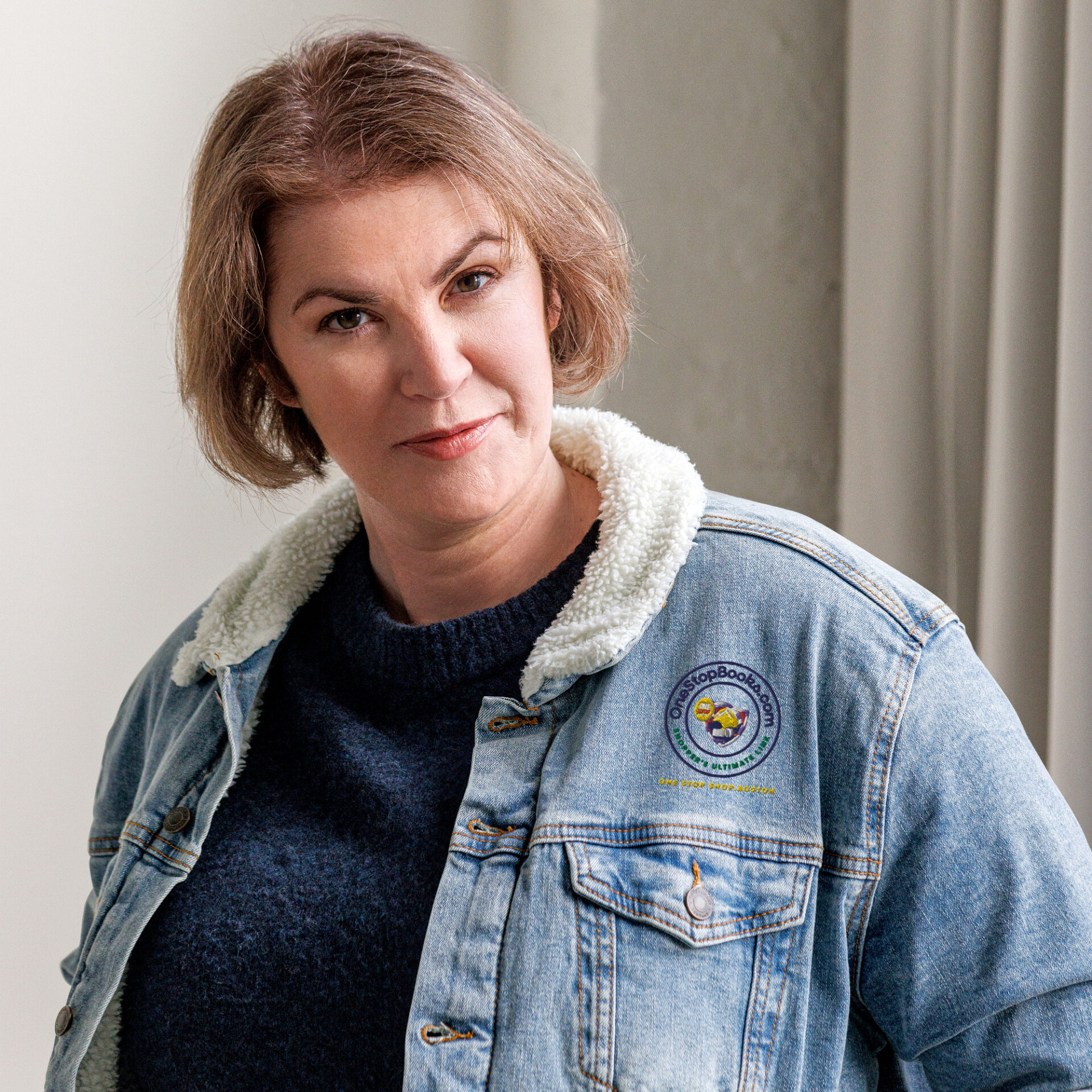 Woman in denim jacket with logo.